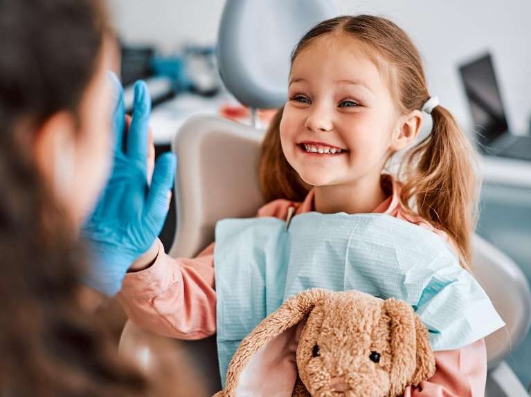 A smiling girl giving her dentist a high five