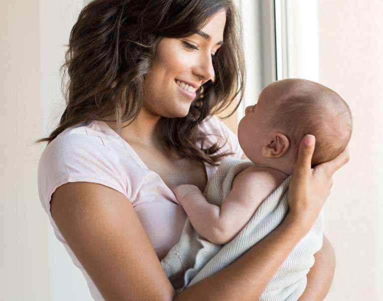 A smiling woman looking at her baby
